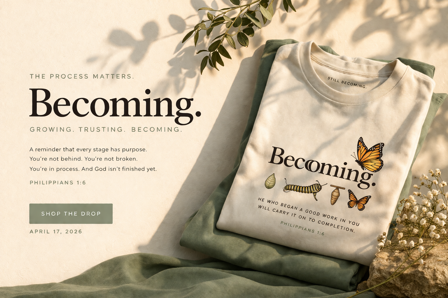 White t-shirt with 'Becoming' design and text, placed on green fabric with nature elements.